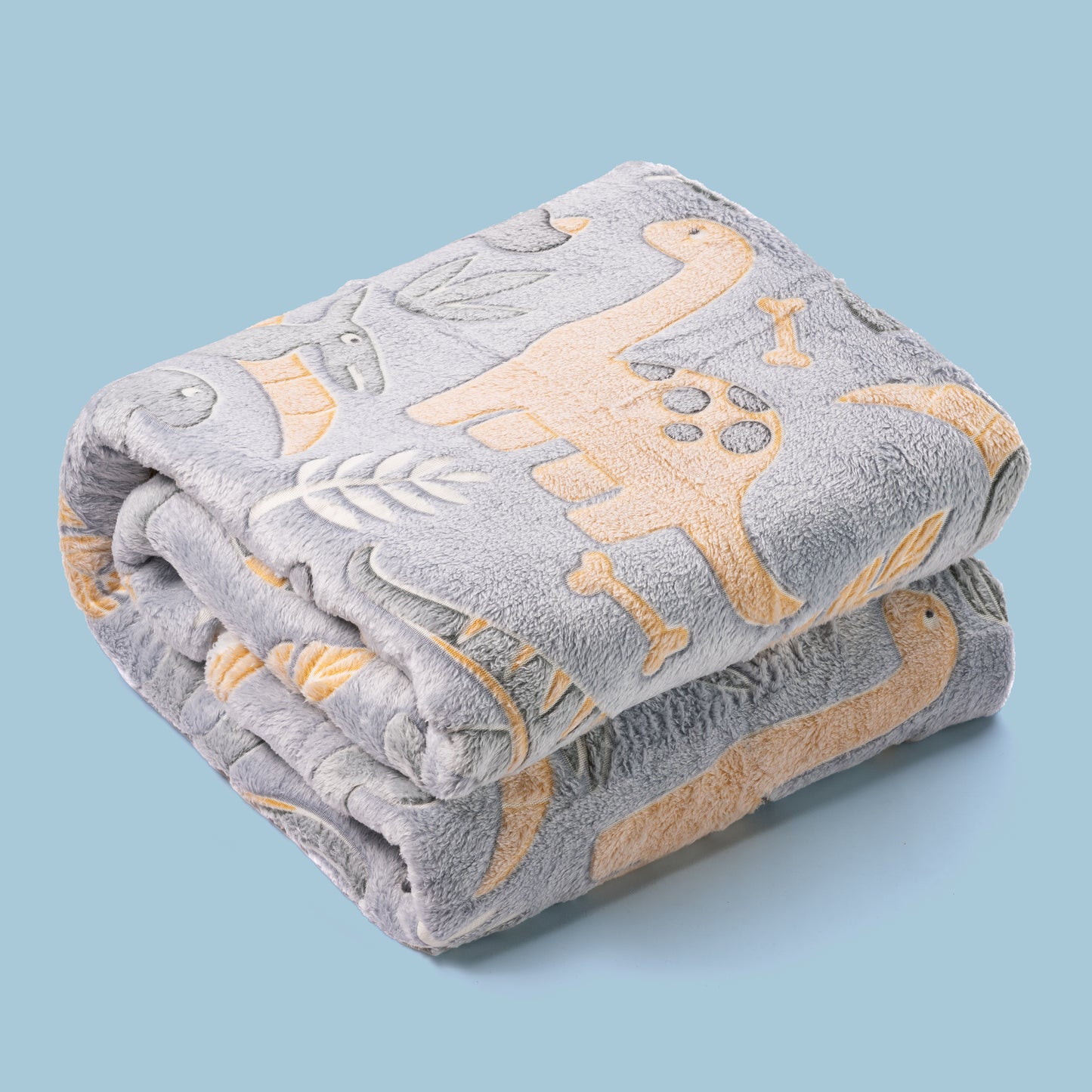 DInosaur blanket that glows in the dark folded on coloured background